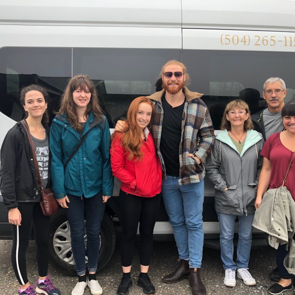 a group of people standing in front of a car posing for the camera